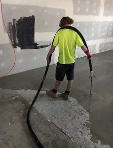 Worker using Mixer plaster rendering machine to coat floar of building