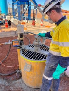 A contractor operating a yellow poly mixing bowl grout pump on-site