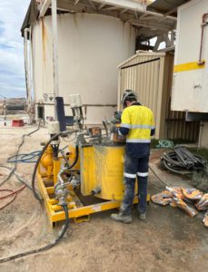 Contractor in safety gear operating grout pump onsite as a part of a contracted project