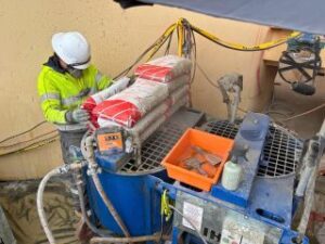 Worker operating a grout pump on site during a grouting contracting job.