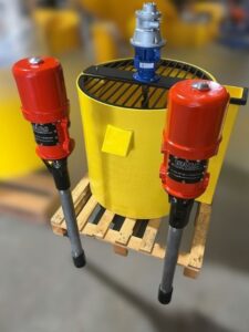 B150b Standard and B150b HP air powered grout pumps positioned beside a poly mixing bowl.